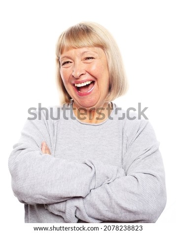 happy pensioner laughs joyfully, a woman is dressed in a blue jumper, experiences joyful emotions, photo on a gray background.