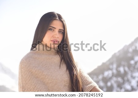 A young Hispanic dark-haired female wearing warm clothes in the snow-capped mountains of Andorra