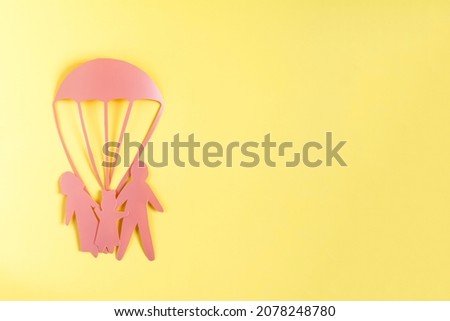 Abstract cardboard family of three and a rescue parachute. Minimalistic picture of family protection in different situations