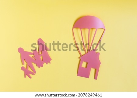 The concept of solving the housing problem of the family. Minimalistic painting of a family and a rescue parachute and a house