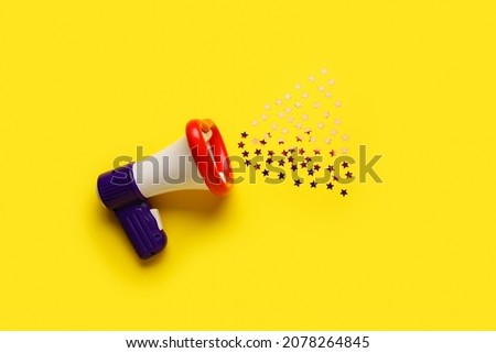 Toy megaphone with confetti on color background