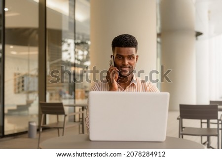 Portrait of young handsome African businessman using laptop computer at coffee shop