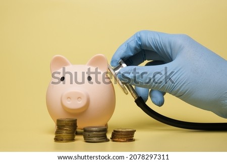 A picture of hand holding stethoscope check the health of piggy bank. Financial health checkup concept. Royalty-Free Stock Photo #2078297311