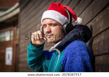 relaxed man with christmas santa hat and headphones listening to music