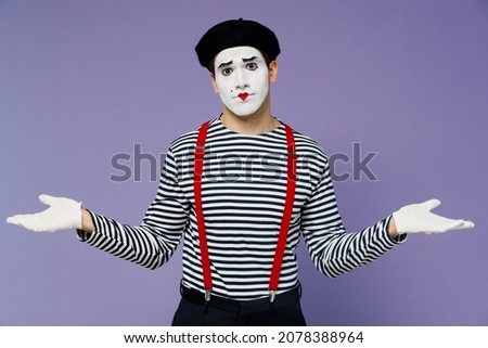Confused perplexed concerned preoccupied young mime man with white face mask wears striped shirt beret looking camera spreading hands isolated on plain pastel light violet background studio portrait
