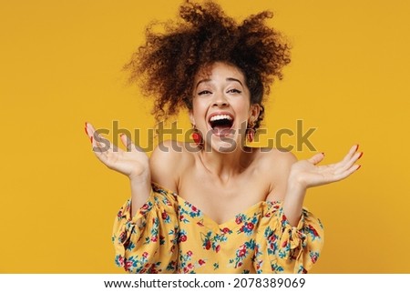 Young happy satisfied excited fun surprised amazed woman 20s with culry hair in casual clothes spread hands look camera isolated on plain yellow background studio portrait. People lifestyle concept Royalty-Free Stock Photo #2078389069