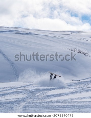 A vertical shot of a snowboarder falling down on a snowy off-piste ski slope Royalty-Free Stock Photo #2078390473