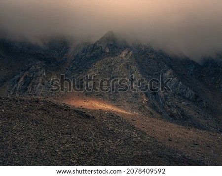 Soft focus. Mystical light in the misty dark mountains. Dramatic sky on mountain peaks. Mystical background with dramatic mountains. 