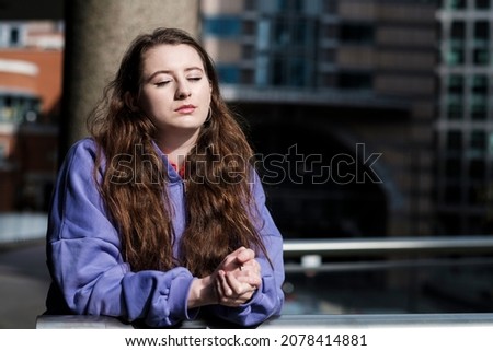 Portrait of a young woman in a purple hooded sweat, financial environment.Relaxed image in London financial district.