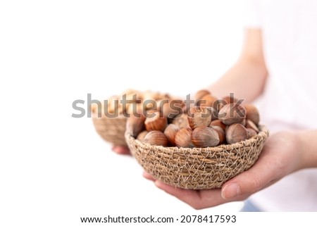 Close-up of a plate of hazelnuts and macadamia nuts in female hands.