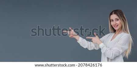 Beautiful blonde woman gesture and sign concept. She points to left side with warm smile. Includes copy space.