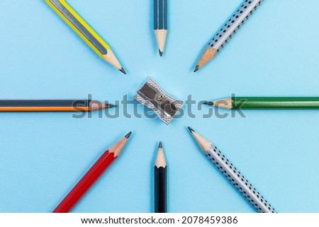 Metal pencil sharpener with Eight different graphite pencils radially set on blue background