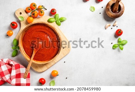 Classic homemade Italian tomato sauce with basil for pasta and pizza. Light gray stone background. top view	