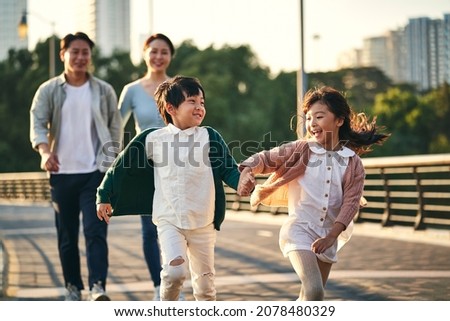 happy asian family with two children walking on pedestrian bridge in city park Royalty-Free Stock Photo #2078480329