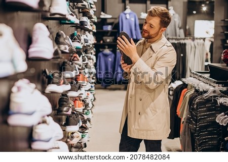Young man choosing sneakers at sportswear shop Royalty-Free Stock Photo #2078482084