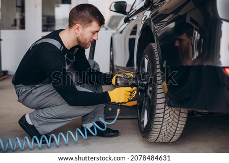 Car mechanic changing wheels in car Royalty-Free Stock Photo #2078484631