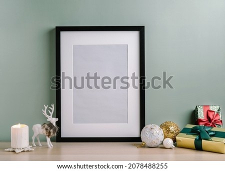 Christmas composition of Christmas decorations, gift box, candle, deer and mock up poster frame for presentation of works and text. Template.