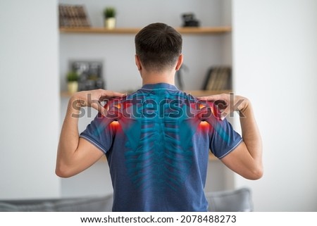 Shoulder-scapular periarthritis, shoulder blades pain, joint inflammation, man with backache at home, human skeleton, painful area highlighted in red Royalty-Free Stock Photo #2078488273