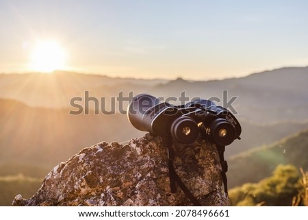 binoculars on top of rock mountain at beautiful sunset background. Royalty-Free Stock Photo #2078496661