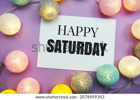 Happy Saturday text with LED cotton balls decoration on purple background