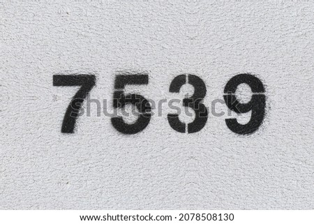 Black Number 7539 on the white wall. Spray paint. Number seven thousand five hundred thirty nine.