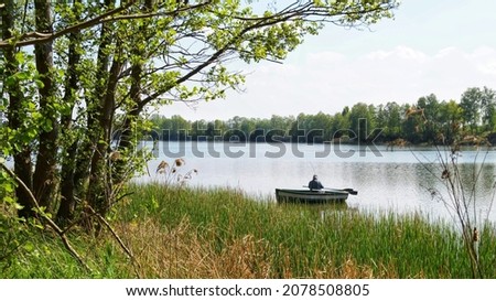 Angler catching fish from a boat on the lake on a sunny summer day  Royalty-Free Stock Photo #2078508805
