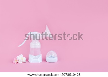 Breast pump and flowers on a pink background. Breastfeeding concept. Copy space