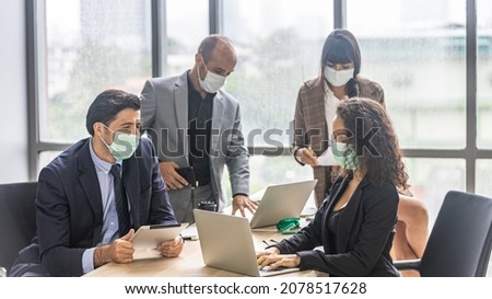 A team of dynamic managers with face masks have a meeting to design for a new business project. Modern office workers use computer and technology for collective decision Royalty-Free Stock Photo #2078517628