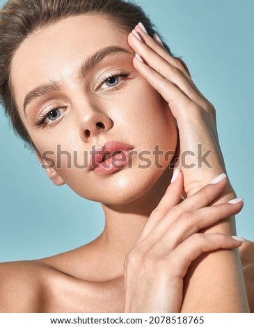Skin care. Beautiful woman with healthy facial skin touching her moisturized face skin, on blue background. High quality Royalty-Free Stock Photo #2078518765
