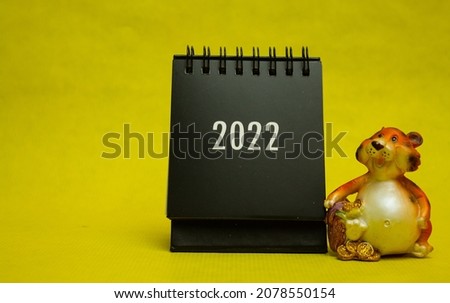 Black desktop calendar 2022, tiger toy, on a yellow table
