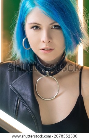 Futuristic portrait. Cyberpunk model. Nightclub style. Gorgeous confident woman with blue hair in LED lamp light in studio background.