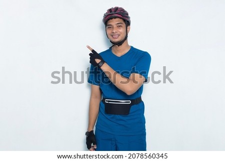 young handsome man cyclist pointing with fingers to different directions on white background