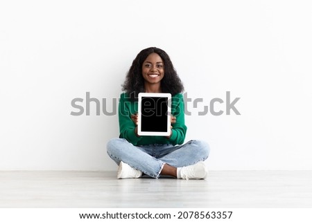 Emotional young black woman showing modern digital tablet with empty screen, newest pad with blank display, mockup, white studio background, various mobile apps for tablets concept, copy space