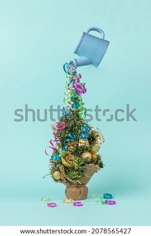 Decorations are poured out of a watering can on a Christmas tree. The minimum concept of the New Year. Contemporary art. Place for text.