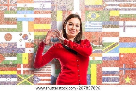 Young pretty girl make a heart with her hands over flags background 
