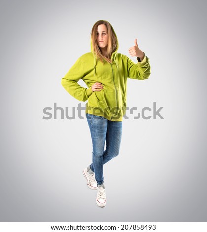 Girl with thumb up over grey background.