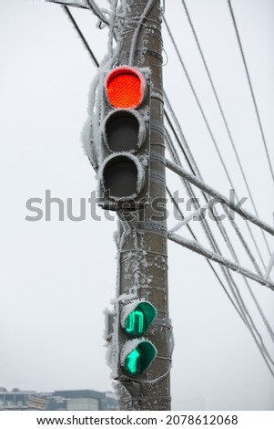 Shot of a frozen red traffic light with blue sky and electrical wires in background. Increase in the number of accidents on an icy road in winter