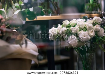 A bouquet of white roses on the window of a flower shop.