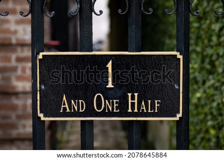 Address sign that reads 1 and one half on a wrought iron fence