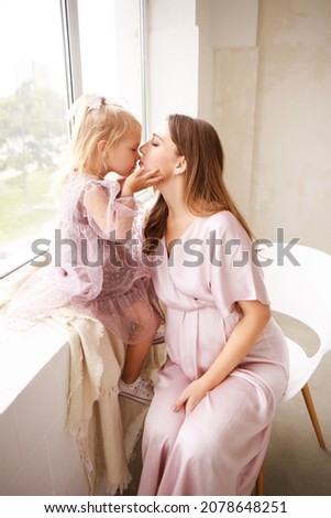 Mother and daughter in delicate outfits hug each other. Mothers Day. 