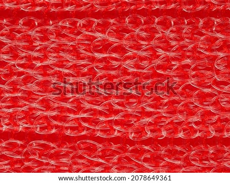 close up, background, texture, large horizontal banner. heterogeneous surface structure bright saturated red sponge for washing dishes, kitchen, bath. full depth of field. high resolution photo