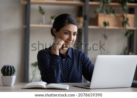 Happy pensive young Indian ethnicity businesswoman looking at computer screen, working on online project on computer at home or office, analyzing electronic document, using software applications. Royalty-Free Stock Photo #2078659390