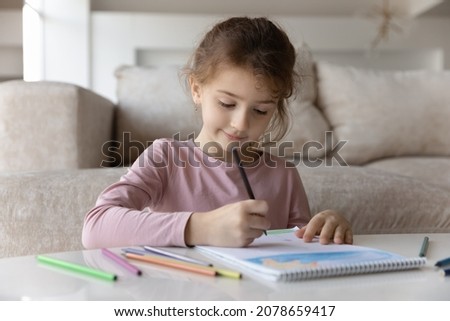 Close up cute preschool little girl kid drawing with colorful pencils in album alone, curious small adorable 7s child engaged in creative activity at home, hobby, painting picture, sitting at table