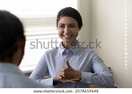 Smiling young Indian woman who is deaf using sign language, communicating with friend or doctor physician, happy attractive female having fun and enjoying pleasant conversation, hard of hearing