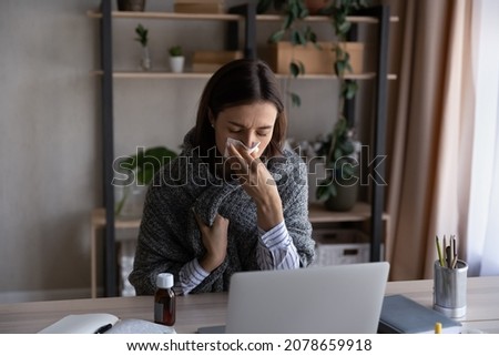 Unhealthy stressed covered in warm plaid young businesswoman using paper tissue, working on computer at home office, suffering from first flu grippe covid19 virus symptoms, self-isolation concept. Royalty-Free Stock Photo #2078659918