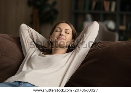 Dreamy peaceful young woman fall asleep relaxing alone on comfy sofa in living room at home, no stress weekend at modern apartment, fresh conditioned air inside, serenity, free time leisure concept Royalty-Free Stock Photo #2078660029