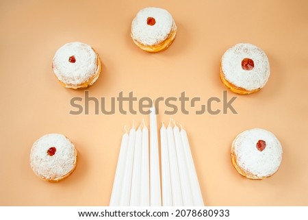 Happy Hanukkah. Traditional Jewish dessert Sufganiyot. Celebrating Judaism holiday. Donuts with jam and sugar powder on beige background.