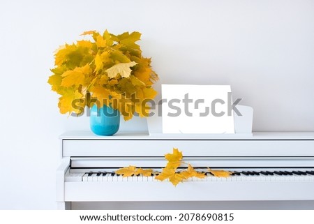 Maple leaves on the piano in a blue vase. The concept of autumn. Front view. Isolated. Russia. Chekhov.