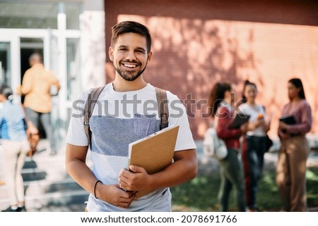 Happy university students standing at campus and looking at camera.  Royalty-Free Stock Photo #2078691766