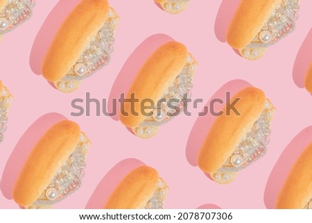 Creative pattern with luxury jewelry in hot dog buns on pastel pink background.  80s or 90s retro aesthetic fashion food concept. Minimal surreal restaurant or fast food idea.